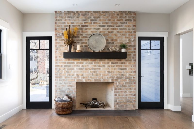 A beautiful, cozy fireplace with natural brick, a wood mantle, and hardwood floors.