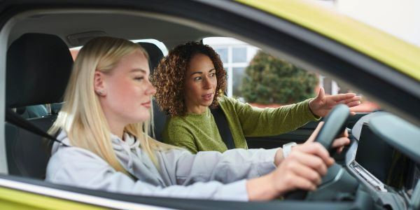 Woman teaching another woman to drive inside a car.