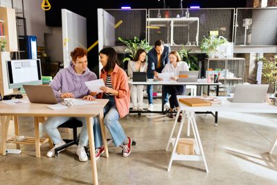 Young professionals collaborating in a modern office space with laptops and documents.