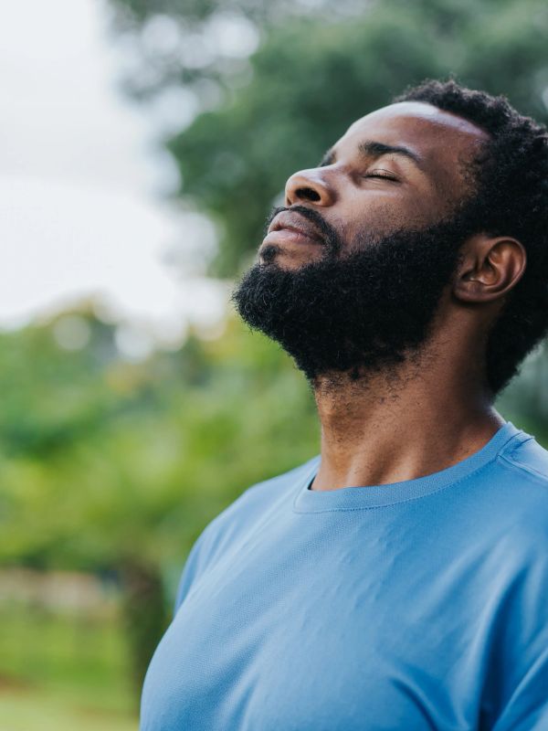 Man in blue shirt enjoying a peaceful moment with closed eyes.