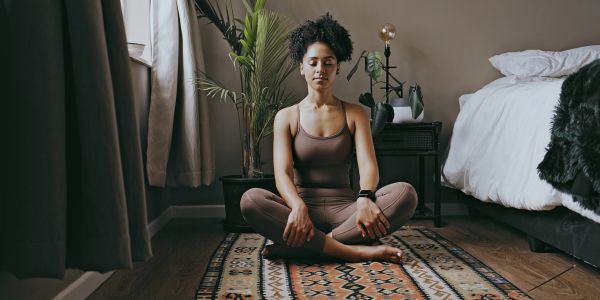 Black woman practicing meditation during a wellness session focused on mental health and self-care.