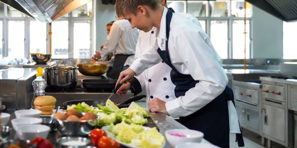 Young chef preparing food in a professional kitchen.