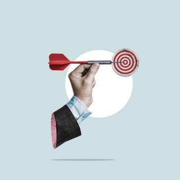 Hand holding dart hitting the bullseye of a target symbolizing Focus