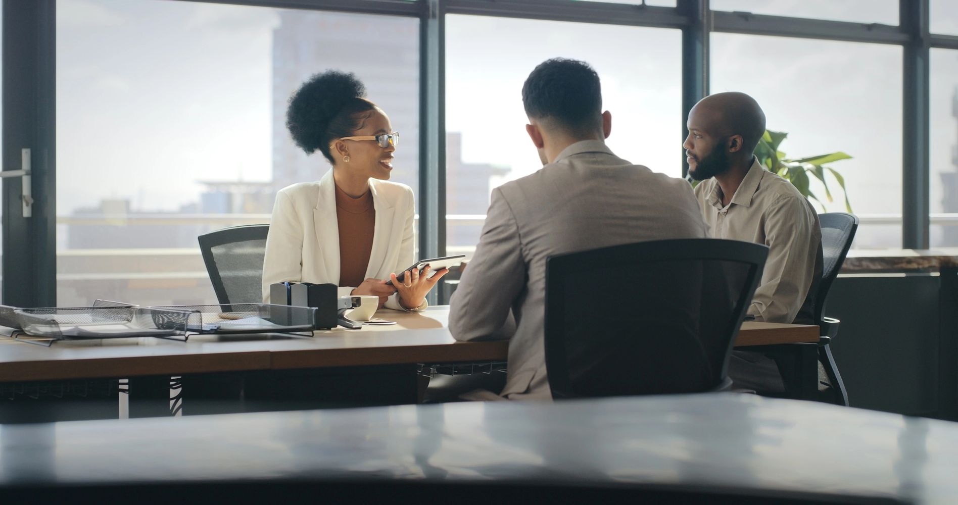 Three colleagues engaged in a discussion in a modern office.
