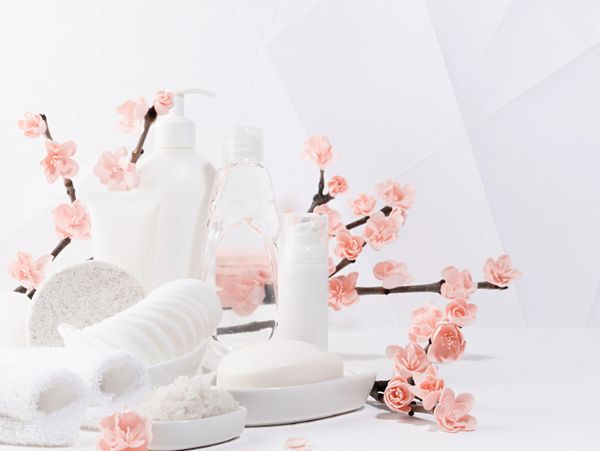 White spa products with pink cherry blossoms on a white background.