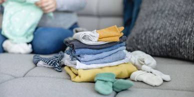 Stack of folded baby clothes on a sofa.