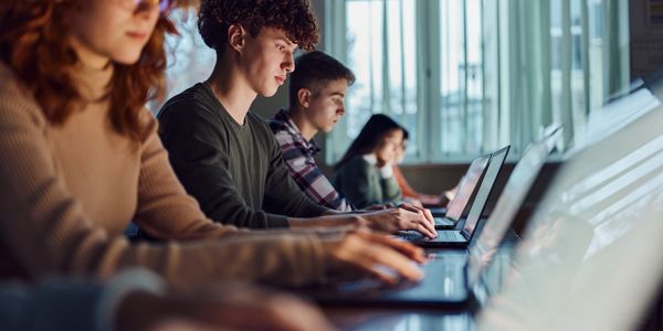 Students focused on working on laptops in a classroom setting.
