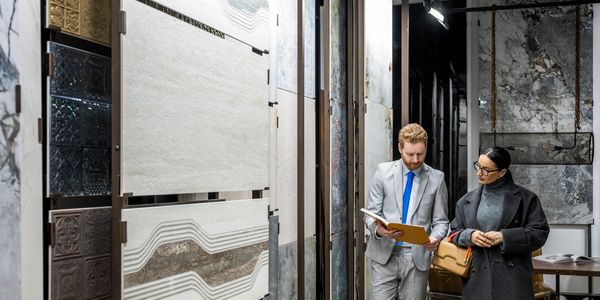 Two people inspect marble slabs in a showroom.