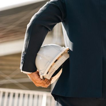 Person in suit holding a white construction helmet.