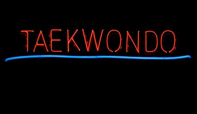 Neon sign that reads 'TAEKWONDO' with a blue underline.