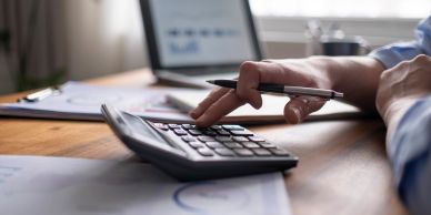 Person using a calculator and pen at a desk.