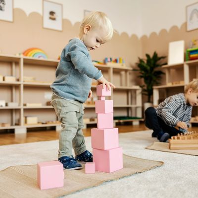 Five children proudly hold up colorful paper crafts in a bright classroom.