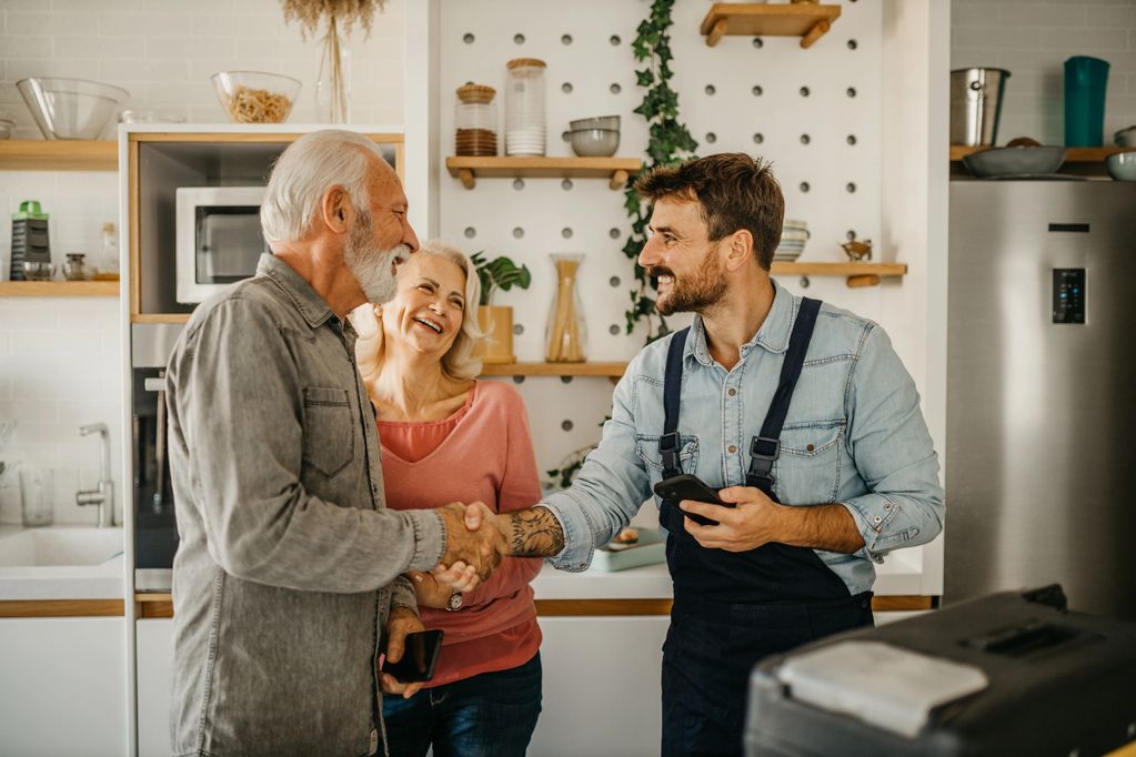 Building tradesman consulting with elderly man and woman