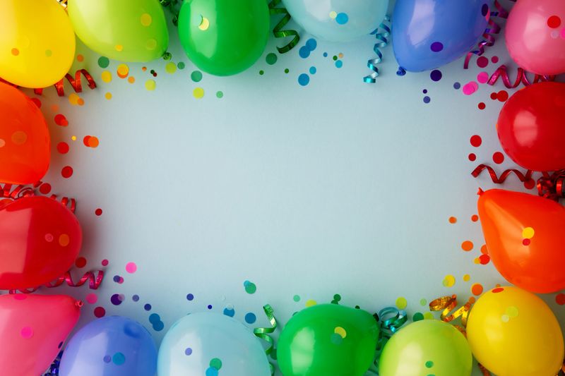 Birthday party background with rainbow border of colorful party balloons with streamers and confetti