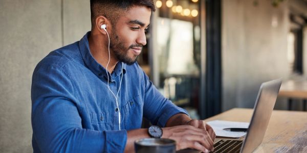 Man working on laptop with earphones.