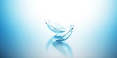 A pair of transparent contact lenses on a reflective surface with blue gradient lighting.