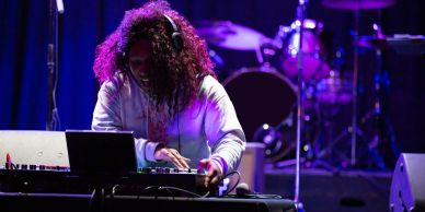 DJ performing live on stage with music equipment.