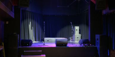Empty small stage with lighting and speakers.