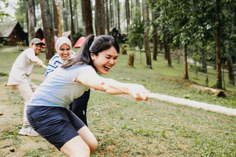 Business team and creative team playing tug-of-war in the forest