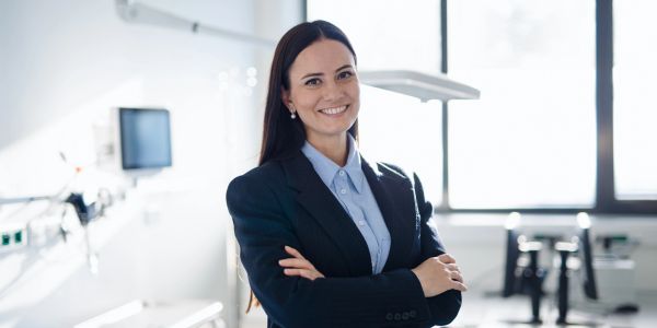 Smiling woman in professional attire with arms crossed.