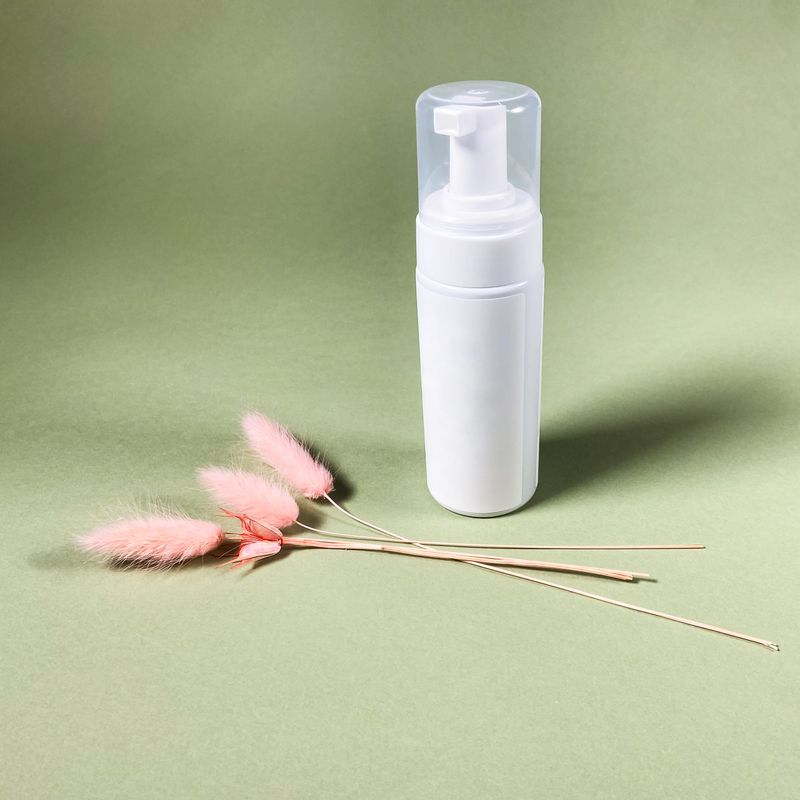 closed white blank pump plastic bottle and natural dried pink spikelets on khaki paper background