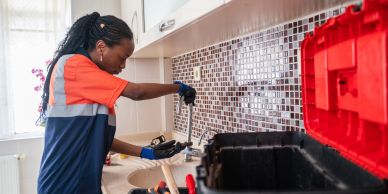 Female plumber working on kitchen sink.