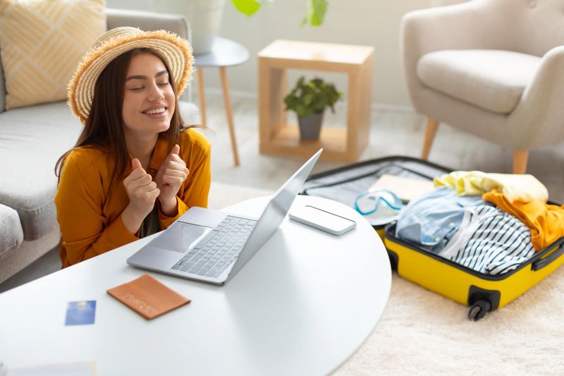 Overjoyed young woman booking hot tour online, excited over huge sale in tourist agency, using laptop to book hotel or buy plane tickets on discount from home, free space. Abroad travel concept