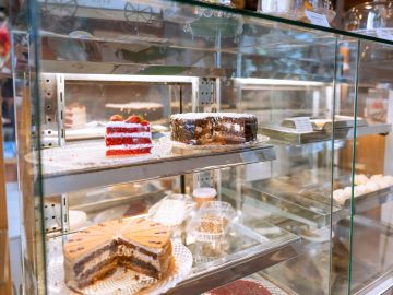 Glass display case with various cakes inside.
