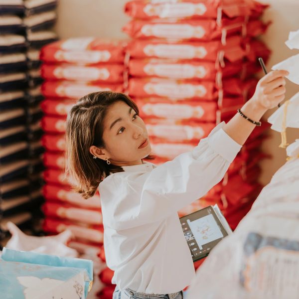 A woman in a white shirt reaching for items in a store aisle.