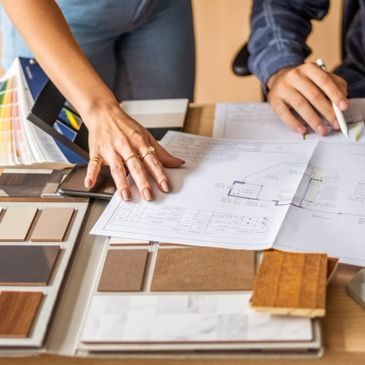 Two people reviewing architectural plans and color samples for interior design.