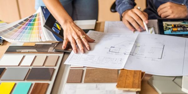 Two people reviewing architectural plans with color swatches and material samples.