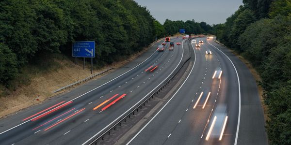 A highway with moving vehicles showing light trails during dusk.