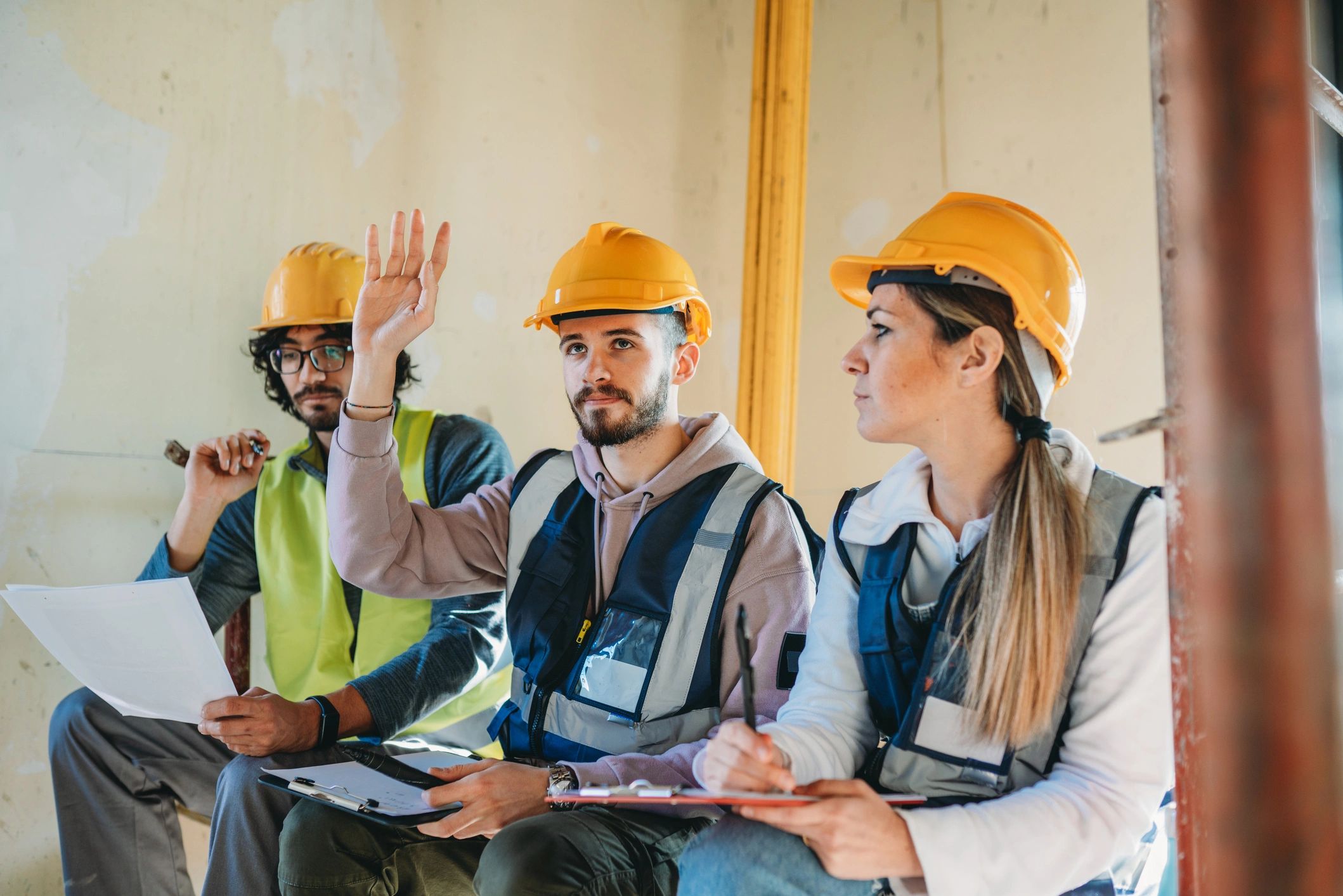 Construction crew in hard hats and vests taking part in a safety meeting