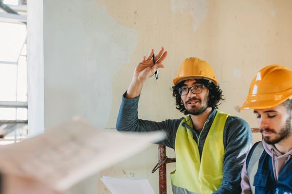 Construction workers in helmets discussing plans during a meeting.