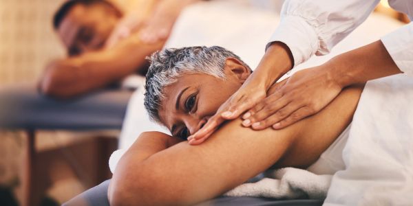 A woman receiving a shoulder massage in a spa setting.