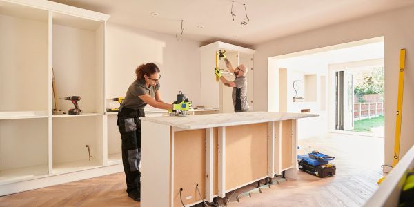 Workers renovating a kitchen by installing cabinets.