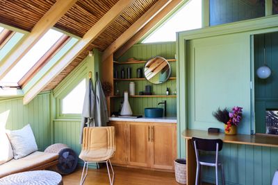 Cozy sunlit room with green walls, wooden ceiling, and modern furniture.