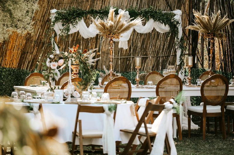Wedding table set up in boho style with pampas grass and greenery of an outdoor wedding reception