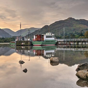 A boat docked at a calm lake with hills in the background.