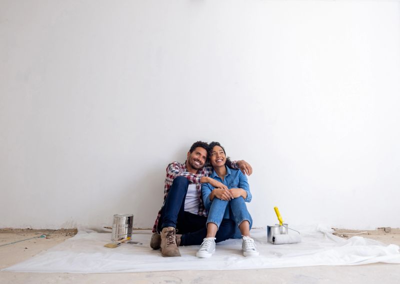 Loving Latin American couple taking a break from painting while remodeling their house