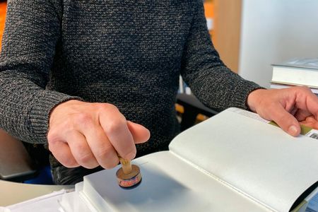 Person stamping a document with a wooden stamp.