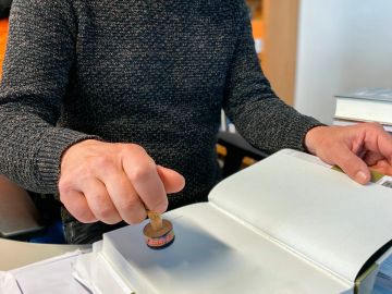 Person stamping a document with a handheld stamp.