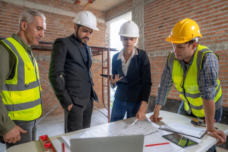 Civil engineer or supervisor inspects and directs workers on a building construction site.