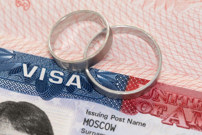 Newlyweds rings on a US visa close-up as an idea of marriage relocation.