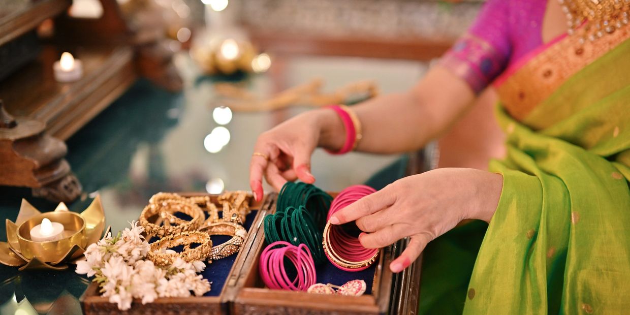 Woman in traditional attire selecting colorful bangles from a jewelry box.