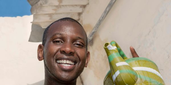A smiling man holding a green and yellow inflatable crocodile.