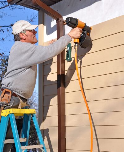 Man using a nail gun on house siding.