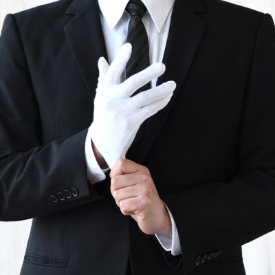 Man in suit putting on white glove.