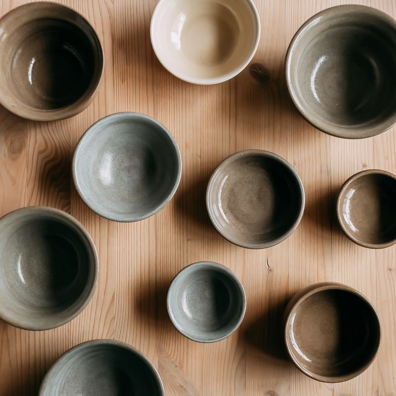 Handmade ceramic craft ware - empty plates and bowls in natural colors on a wooden table. Top view