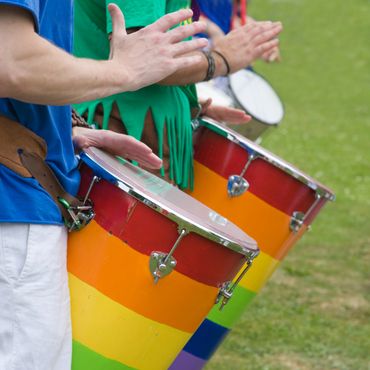 People playing colorful rainbow drums in an outdoor setting.